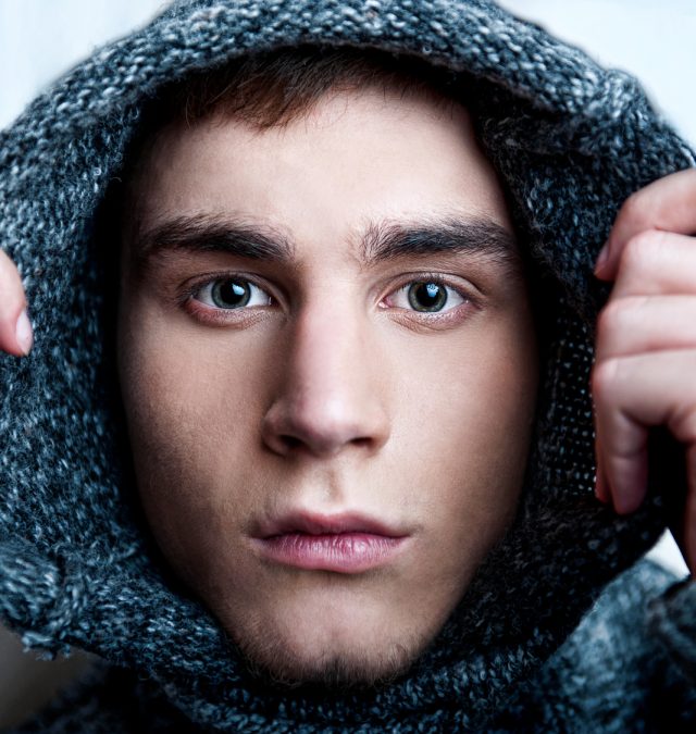 Portrait of young handsome man putting on warm pullover and look should you be vulnerable