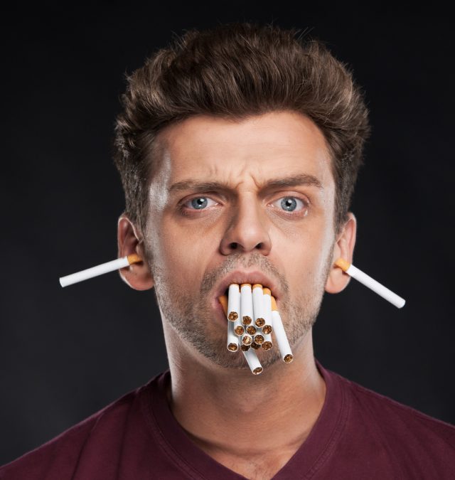 Man holding many cigarettes in his mouth. guy with bad smoking habits