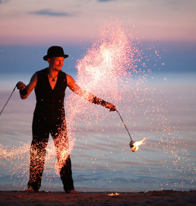 Showman spinning fire poi, sparks of fire guy showing how to make an impact